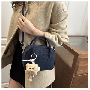 Detail of dark blue leopard print crossbody bag with cute plush pendant on model