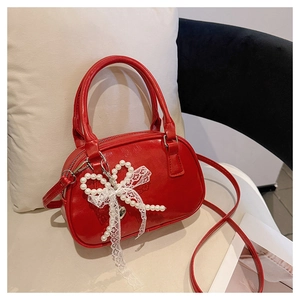 Detail of red bowling bag with glossy finish and pearl lace bow charm decoration