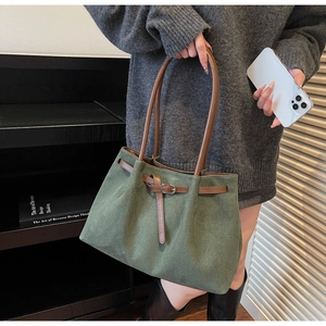 Detail of dark green suede tote bag with brown leather straps and vintage buckle design