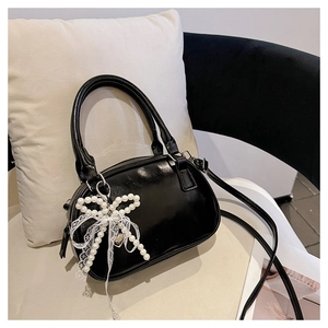 Close-up of black patent leather bowling bag with pearl bow charm and silver hardware
