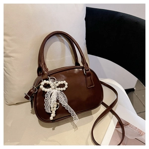 Close-up of deep brown glossy faux leather bowling bag with pearl bow and lace charm