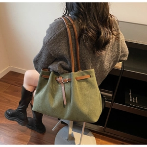 Detail of green suede tote bag showing brown leather shoulder straps and buckle detail