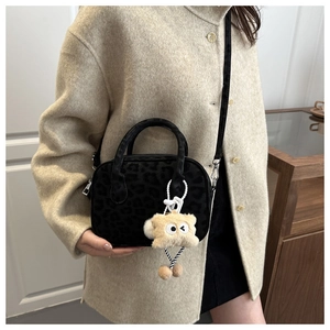 Detail of black leopard print crossbody bag with furry monster charm and silver metal hardware