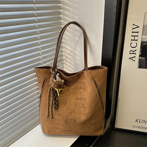 Brown vintage tote bag with cute cartoon illustrations and plush bear charm in sunlight