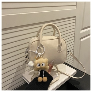 Detail van beige imitatielederen Boston tas met een schattige pluche koekjes hanger