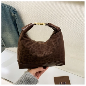 Detail of retro brown faux leather handbag with subtle leopard print and gold metal buckle