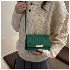 Détail du sac à main vert forêt à motif crocodile et boucle métallique dorée élégante