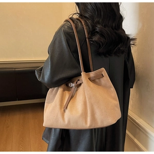 Detail view of large camel suede tote bag with leather straps on model's shoulder