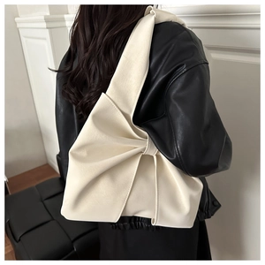 Close-up of off-white tote bag featuring a large decorative side bow knot detail