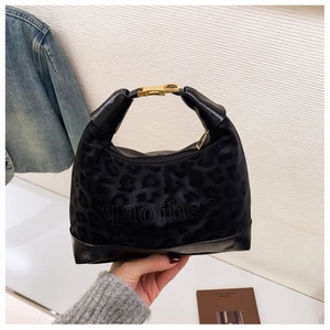 Detail of black leopard print textured fabric with gold rectangular clasp on shoulder bag