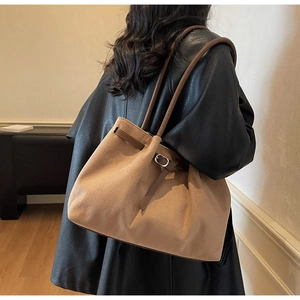 Detail of a large brown faux suede tote bag featuring a drawstring and metal buckle