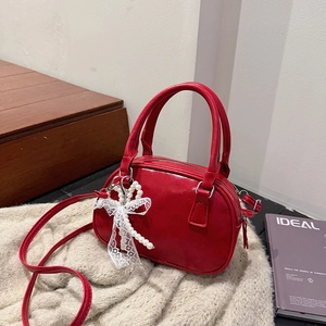 Red Boston style faux leather handbag with pearl lace bow charm on a soft background