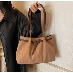 Detail of vintage brown suede tote bag with leather straps and buckle on shoulder
