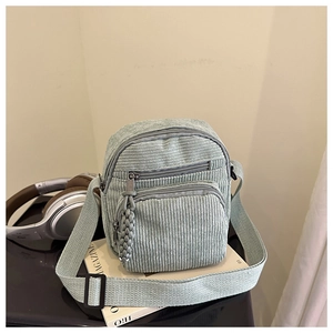 Détail du sac bandoulière en velours côtelé vert clair avec poches zippées et sangle