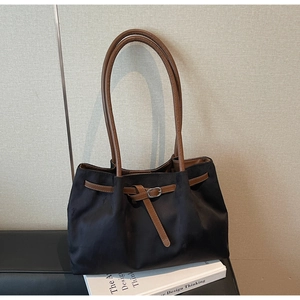 Detail of suede tote bag featuring brown leather trim and decorative belt buckle