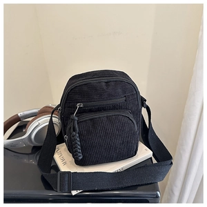 Détail de la bandoulière en velours côtelé noir avec sangle réglable et tirettes texturées