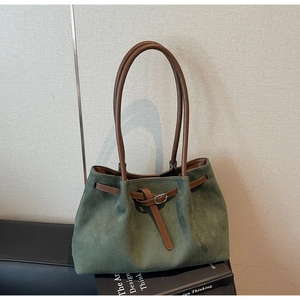 Detail of dark green suede tote bag with brown leather strap on minimalist books