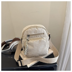 Détail du sac bandoulière en velours côtelé crème avec poches zippées et tirettes tissées