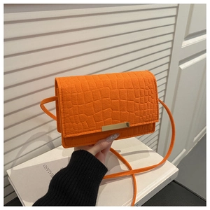 Vue détaillée du cuir crocodile orange vif sur un petit sac à bandoulière carré à rabat