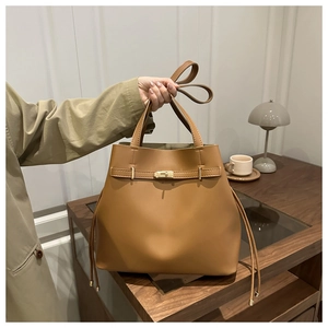 Détail d'un sac seau marron avec un fermoir rotatif doré et des cordons latéraux