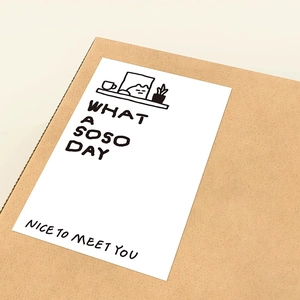 Minimalist white square cat sticker with black text on a brown cardboard box surface