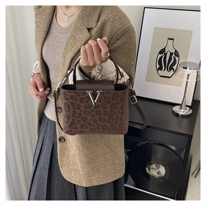 Détail du sac léopard avec garniture en cuir marron et boucle métallique dorée en forme de V