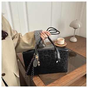 Détail du sac cabas noir à texture léopard avec logo FASHION et pendentifs élégants
