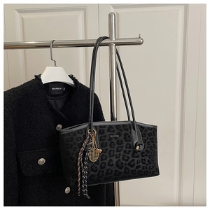 Détail d'un sac cabas léopard avec breloque raquette de tennis dorée et lettrage mode