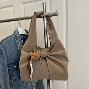 Sac fourre-tout marron avec grand nœud et breloque ours sur un cintre minimaliste