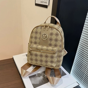 Eleganter beiger Mini-Rucksack mit M-Muster und Golddetails in Gold auf einem Holztisch