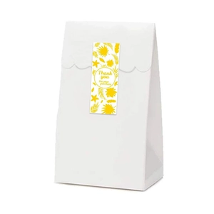 White cardstock gift bag with gold foil thank you sticker and yellow tropical leaf pattern