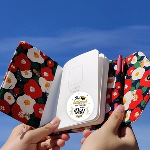 Ensemble carnet en tissu motif chat et fleurs avec stylo sur fond de ciel bleu clair