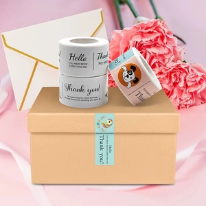 Detail view of rectangular gold foil Thank You stickers on gift boxes with floral accents