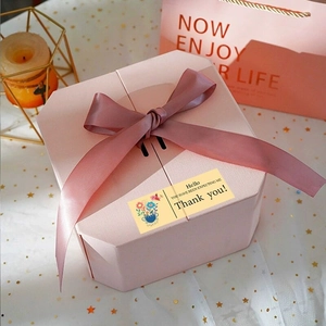 Detail of a pink hexagonal gift box with satin ribbon bow and gold foil Thank You sticker