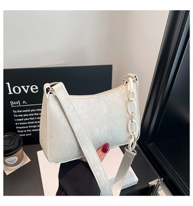 Detail of cream white corduroy handbag featuring textured folds and a resin chain strap