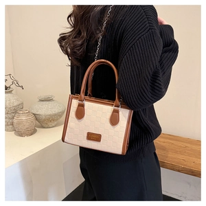 Detail of cream waffle embossed tote bag worn by a model in a minimalist indoor setting