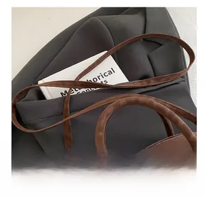 Detailed close-up of the adjustable strap and sturdy handle on this brown suede handbag