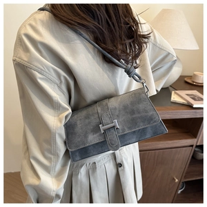 Detalle de bolso bandolera gris de ante con hebilla plateada y correa con nudo de moda