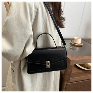 Classic black leather crossbody bag featuring an elegant gold metal lock and shoulder strap