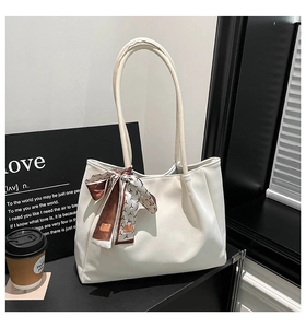 Détail du sac cabas en cuir blanc avec un élégant foulard en soie sur la poignée