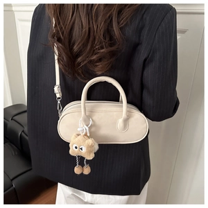 Detail of cream pillow bag with star plush charm worn by model in a minimalist setting