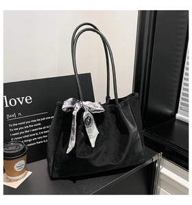 Gros plan sur un grand sac cabas noir mat orné d'un foulard en soie décoratif