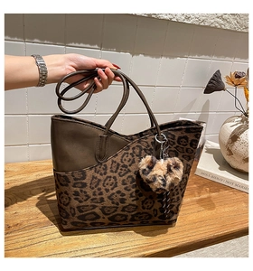 Detail der Leoparden-Tote-Bag mit Plüsch-Herzanhänger und braunen Lederriemen