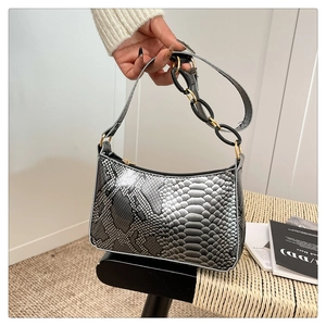 Détail du sac à bandoulière argenté à motif serpent avec chaîne noire et fermeture