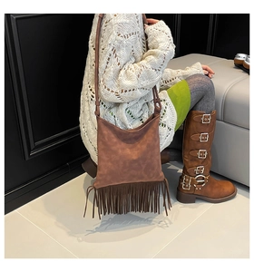 Vue détaillée d'un sac à bandoulière en daim marron avec de longues franges sur un modèle