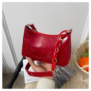 Detail of red snake pattern handbag with elegant gold hardware and bold acrylic chain