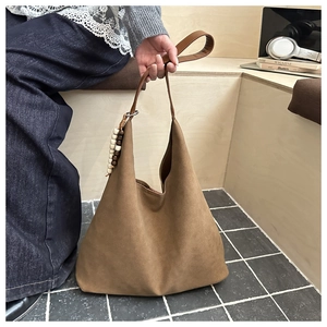 Detailed macro view of retro brown suede tote bag with decorative wooden beads and strap