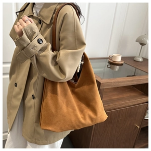 Detail of large brown suede tote bag with decorative side beads and dark leather strap