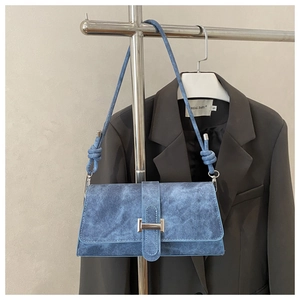 Primer plano del bolso baguette de mezclilla azul con hebillas plateadas y nudos