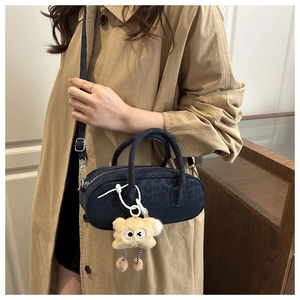 Detail of navy blue suede shoulder bag with leopard print and plush monster charm accessory